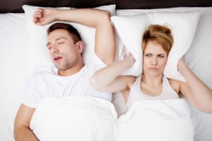 Snoring man and young women sleeping in bed