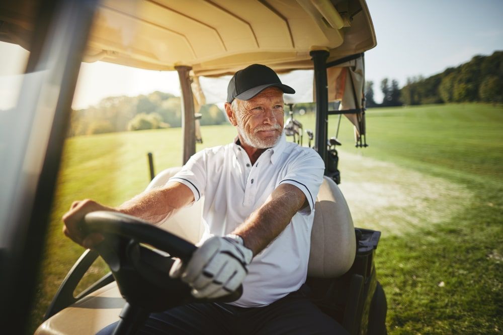 Smiling senior man driving a golf cart