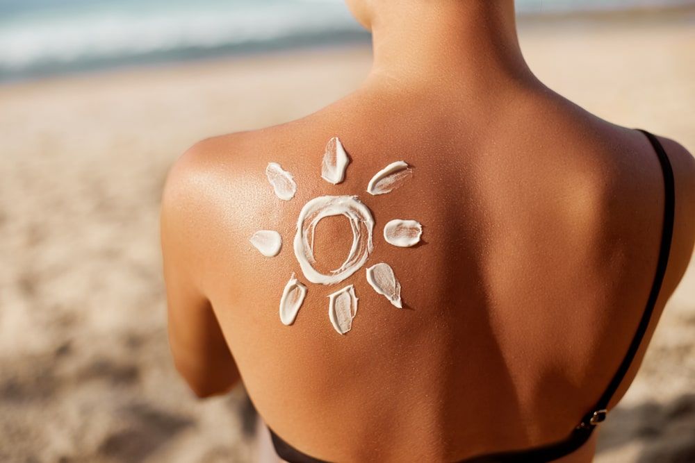 Woman Applying Sun Cream on Tanned Shoulder In Form Of The Sun