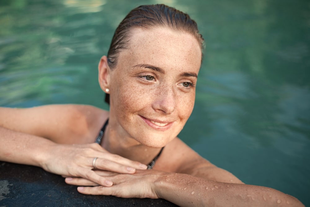 beautiful girl with sunspots and wet hair in water