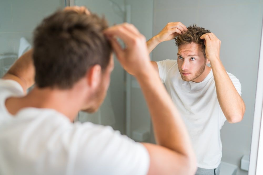 Hair loss man looking in bathroom mirro