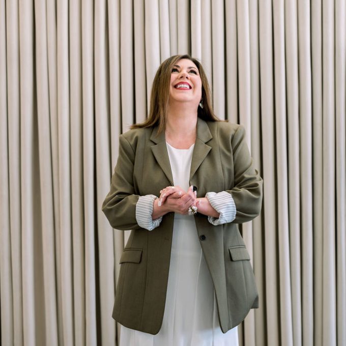 Aileen Nealie is standing infront of curtain, smiling and looking up