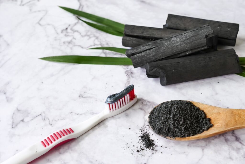 burnt wood, charcoal powder, and toothbrush with charcoal toothpaste