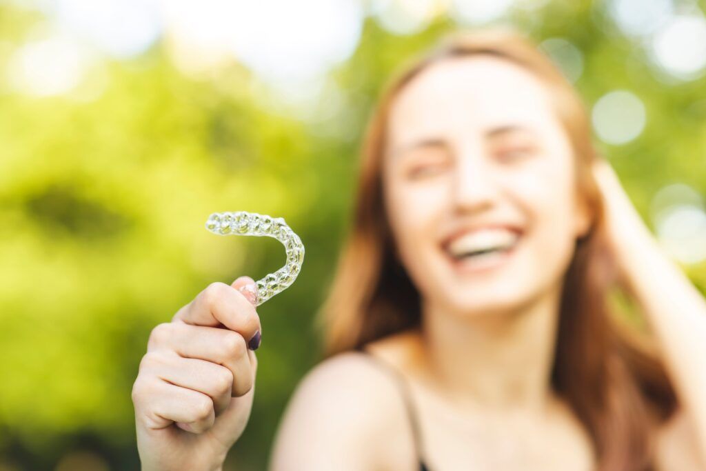 Beautiful smiling Turkish woman is holding an invisalign bracer with vibrant colors