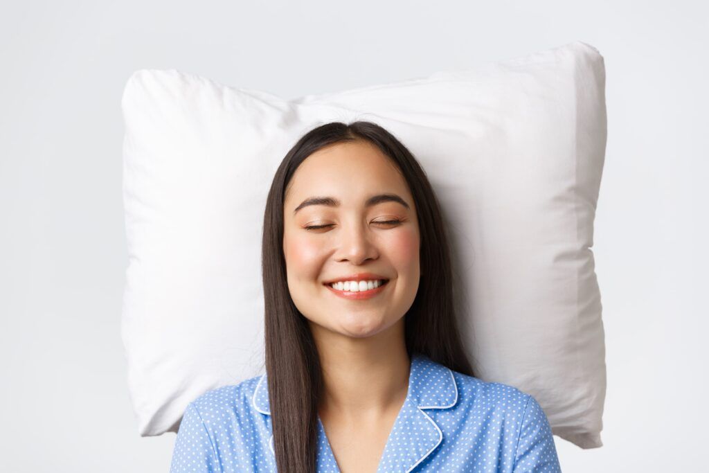 sleepy woman smiling with her head on a pillow