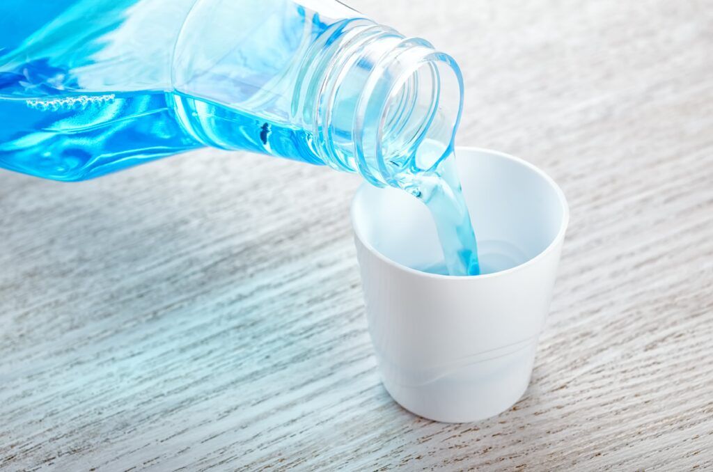closeup of blue mouthwash being poured in cup