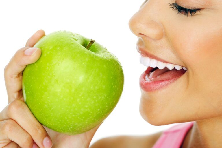 side profile of woman biting into green apple