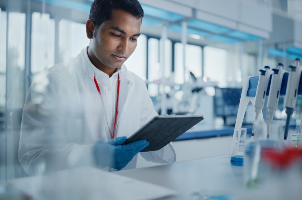 Portrait of a Handsome Male Scientist Using Digital Tablet Computer to Analyse Data.