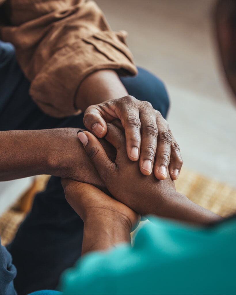 Closeup shot of a young woman holding a senior man's hands in comfort.