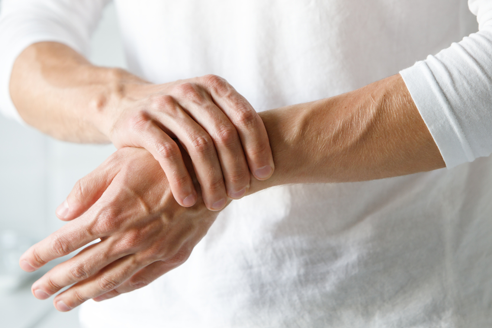 Closeup of male arms holding his painful wrist caused by