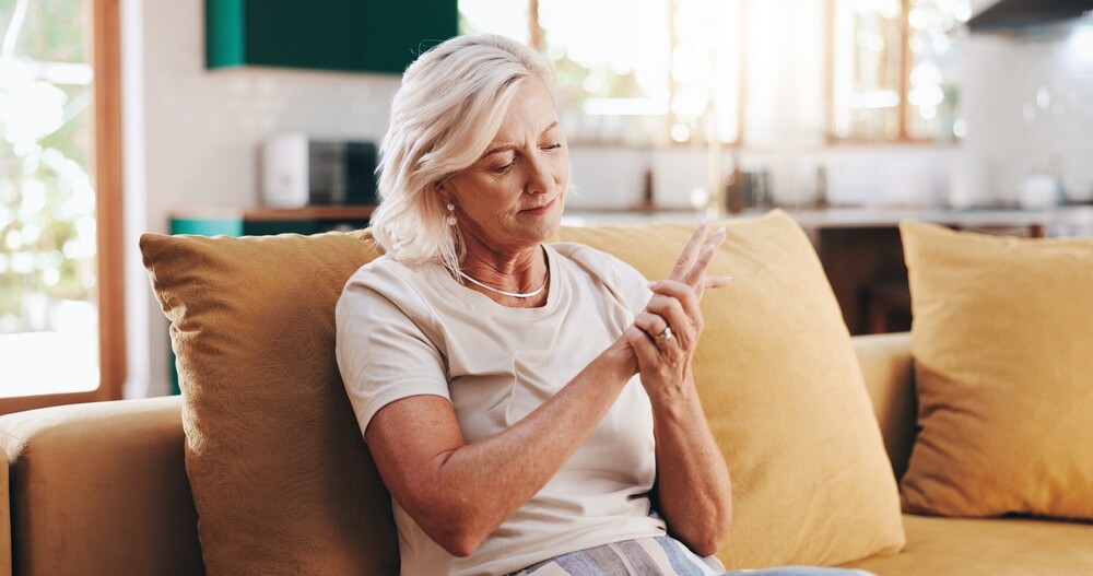 Senior woman, hand pain and arthritis in home, orthopedic joint inflammation and check wrist damage