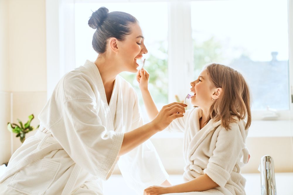 Mother and daughter child girl are brushing teeth