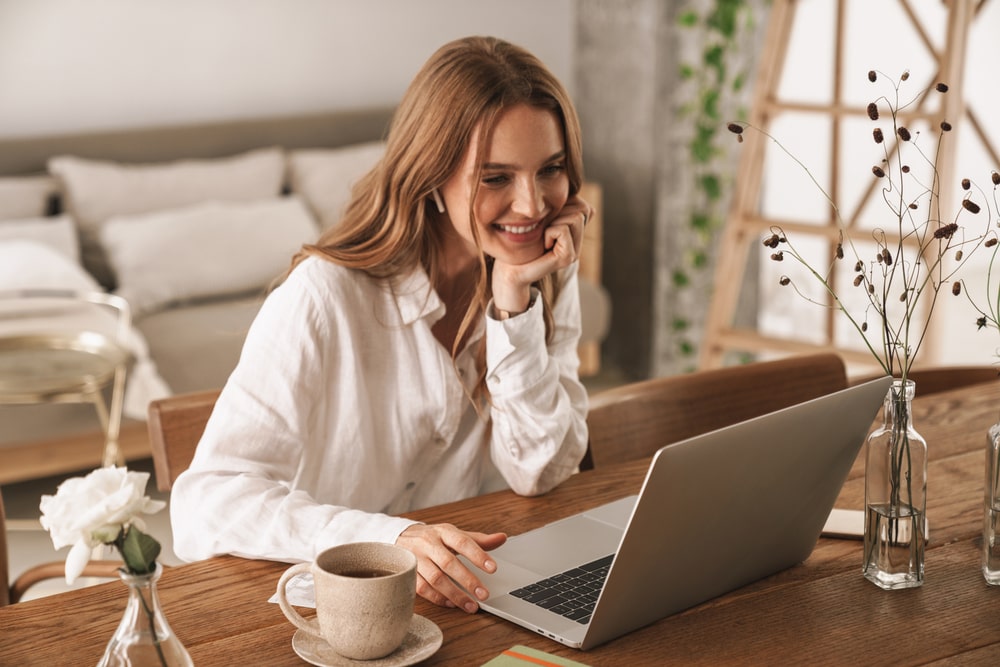 happy cheerful cute woman indoors in office using laptop