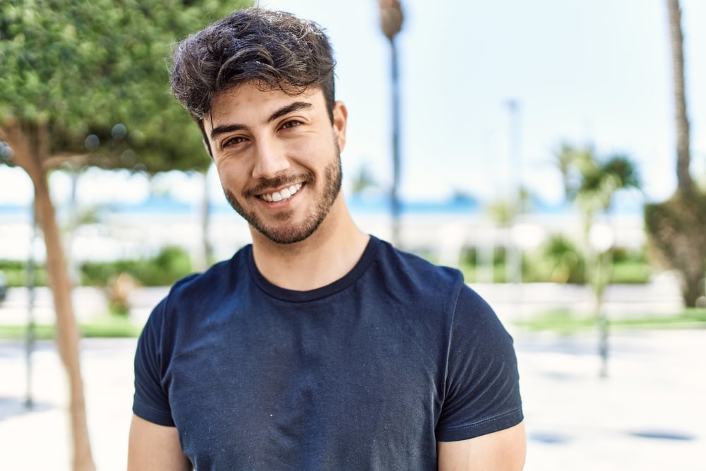 Young man smiling happy standing at the city.