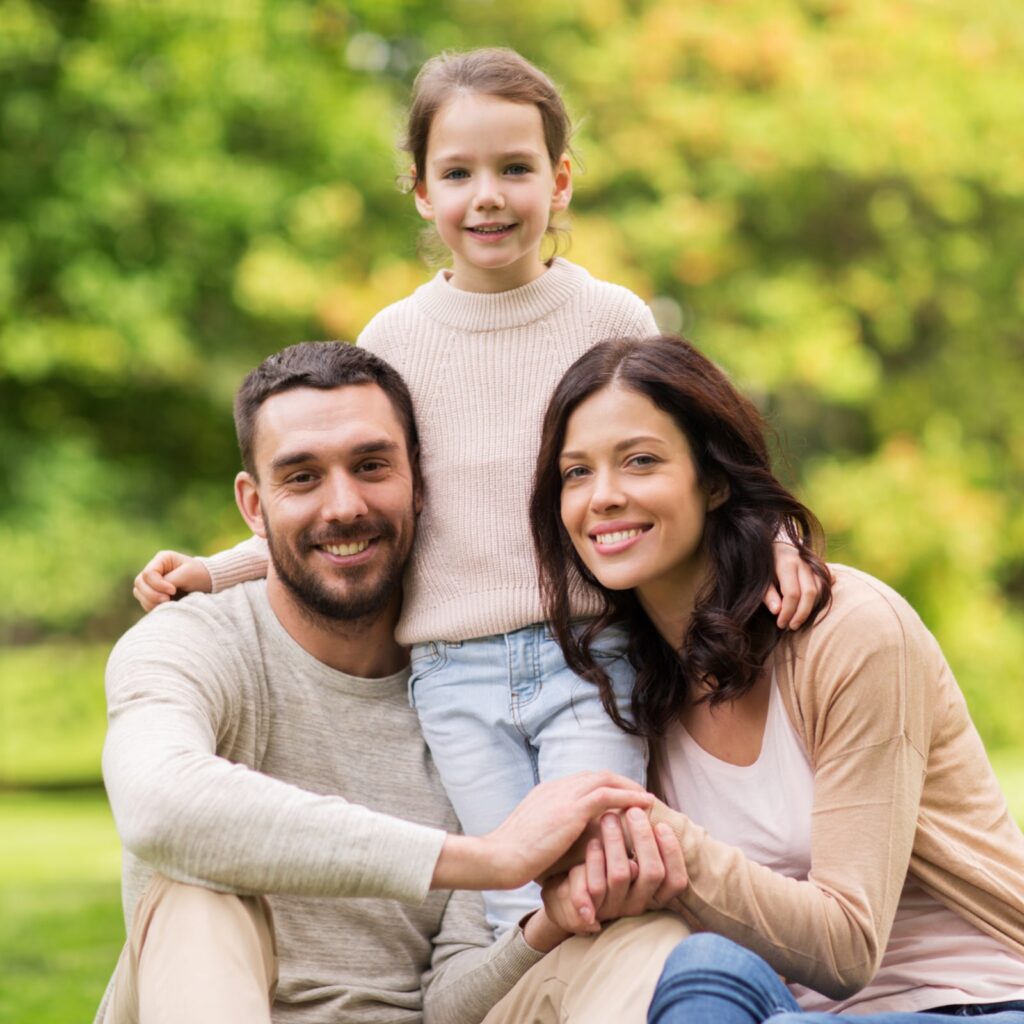 happy mother, father and little girl in summer park