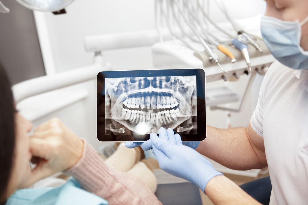 Dentist showing jaws and teeth x-rays to his patient