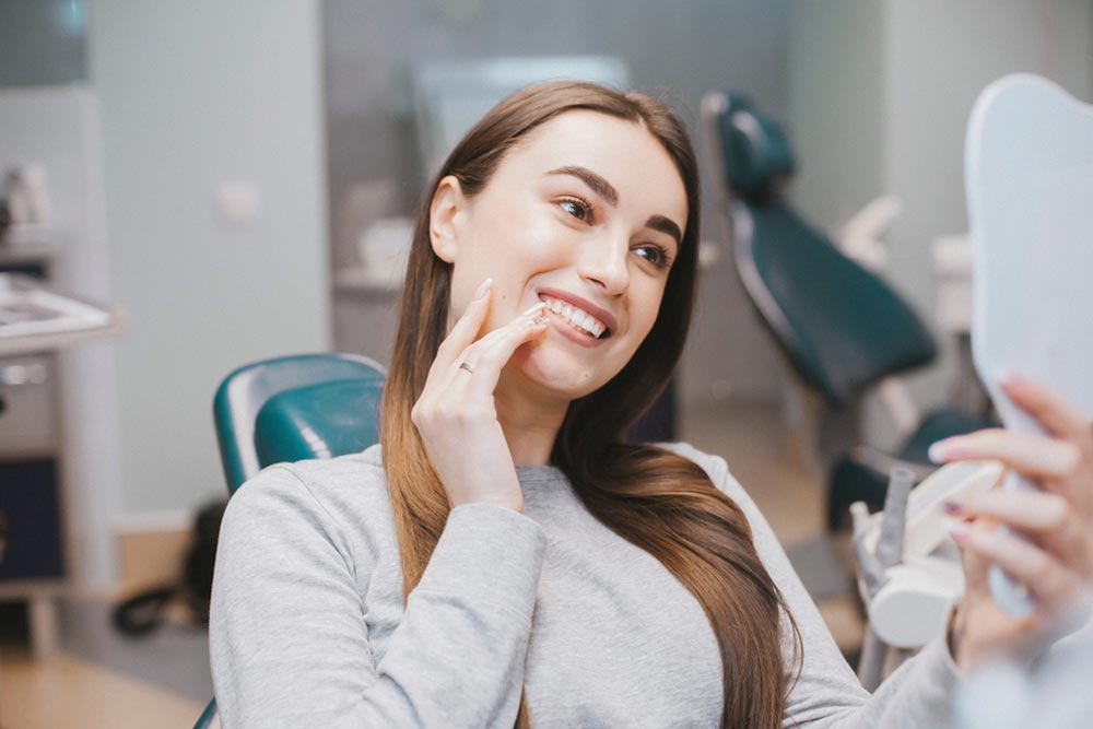 Female patient smiling and looking in mirror