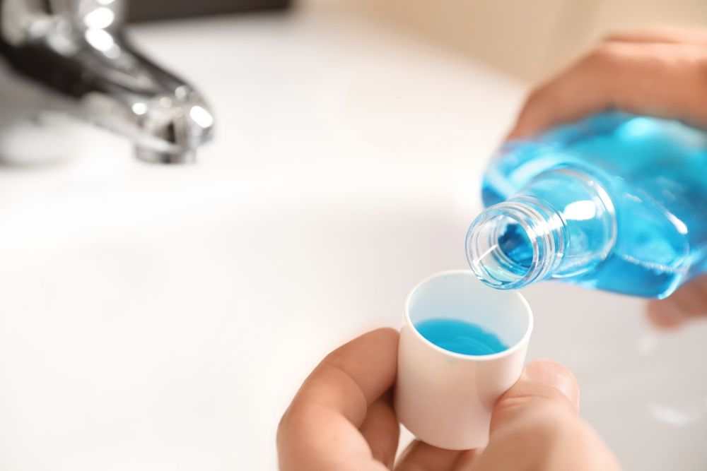 Man Pouring Mouthwash From Bottle Into Cap In Bathroom Closeup.