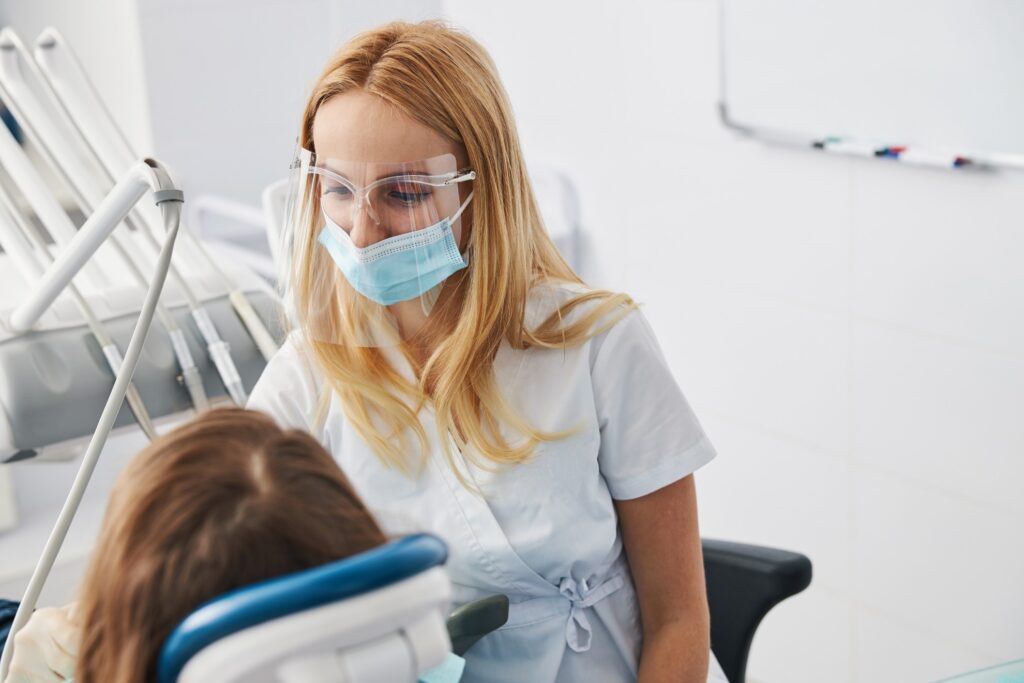 Blonde dentist at clinic treating patient