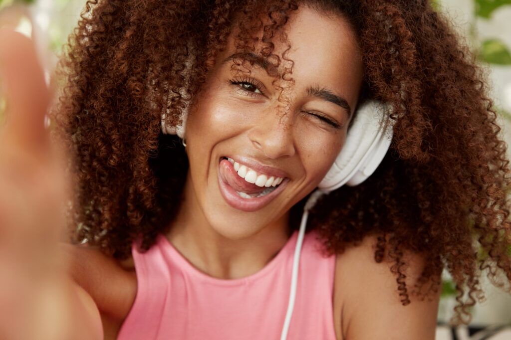 Close up shot of cheerful African American female listens pleasant music