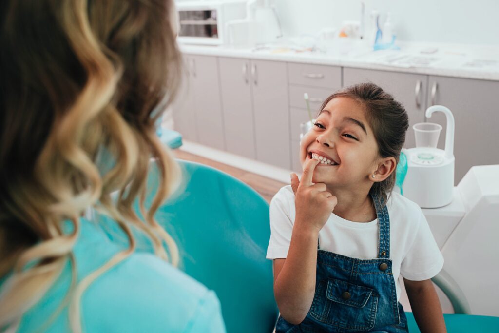 Little patient showing her perfect toothy smile while sitting dentists chair