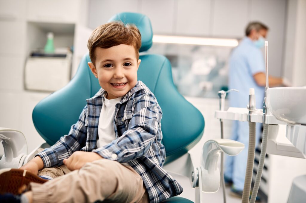 Cute kid sitting in dentist's chair and looking at camera.