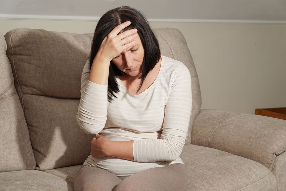 Middle aged mature pregnant woman suffering from headache and stomach ache