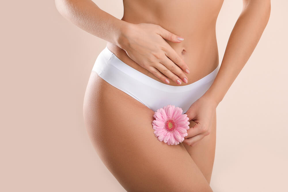 Young woman with flower on light background. Gynecology concept