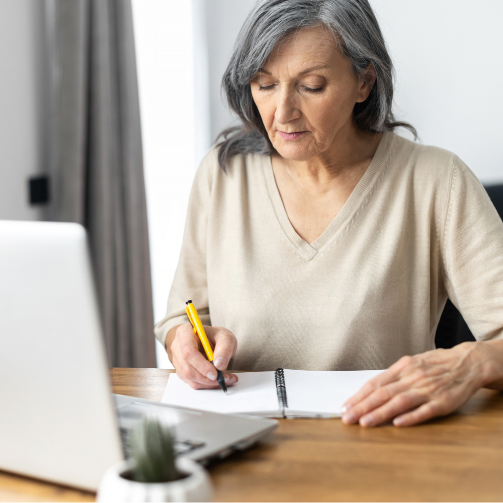 Mature focused woman watching online webinars on the laptop