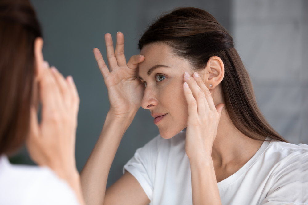 Woman looking in mirror check face after facelift