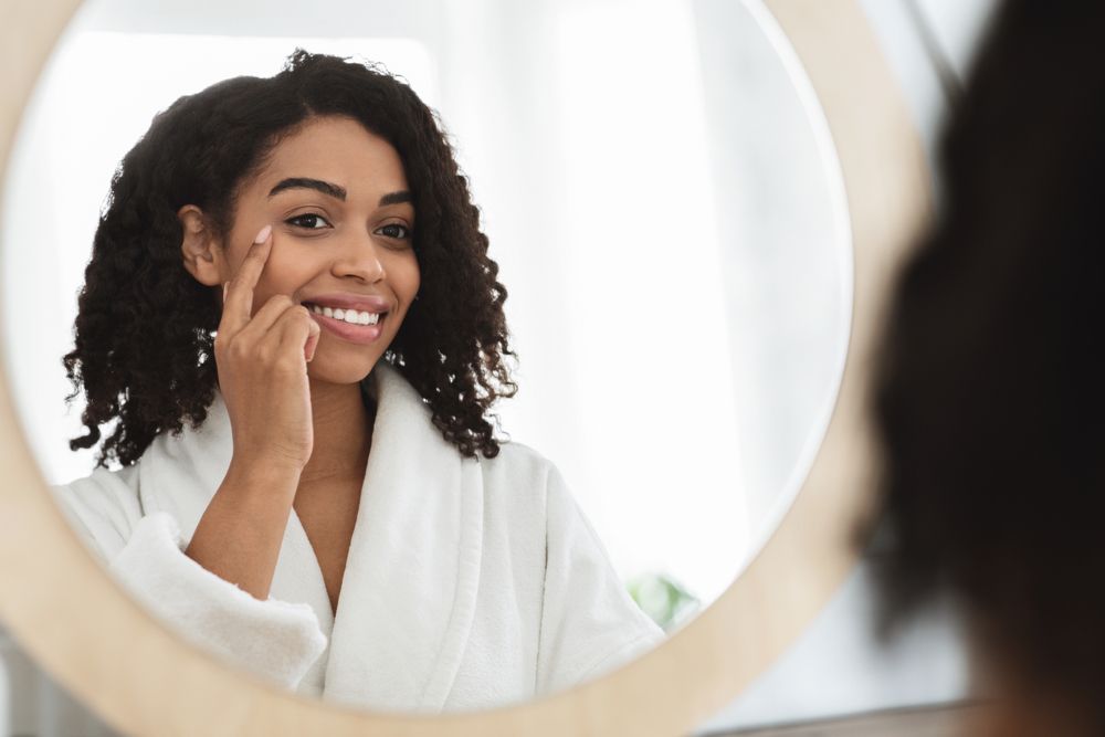 A woman looking at the mirror smiling after getting an Browlift