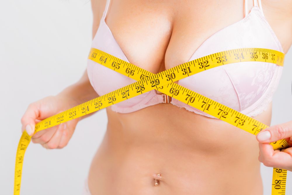 Woman with measuring tape around her breasts thinking about a Breast Reduction