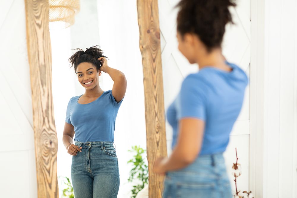 Woman smiling in the mirror after recovering from Fat Grafting surgery