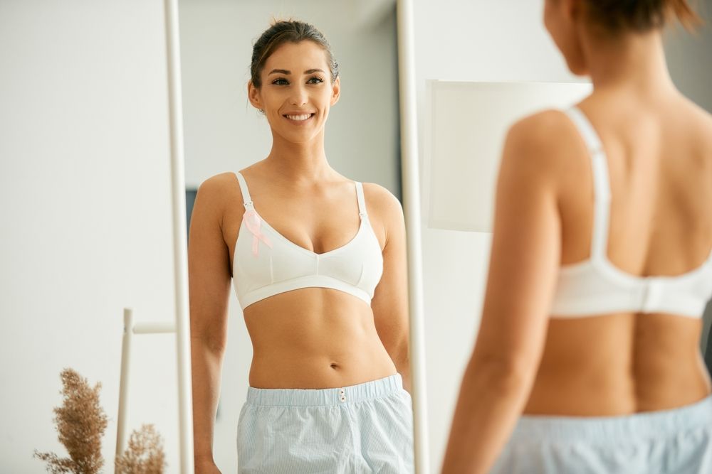 Woman looking in the mirror after receiving a Partial-Breast Reconstruction