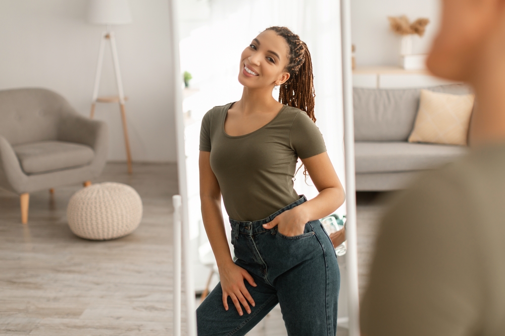 A woman smiling in the mirror after getting Liposuction