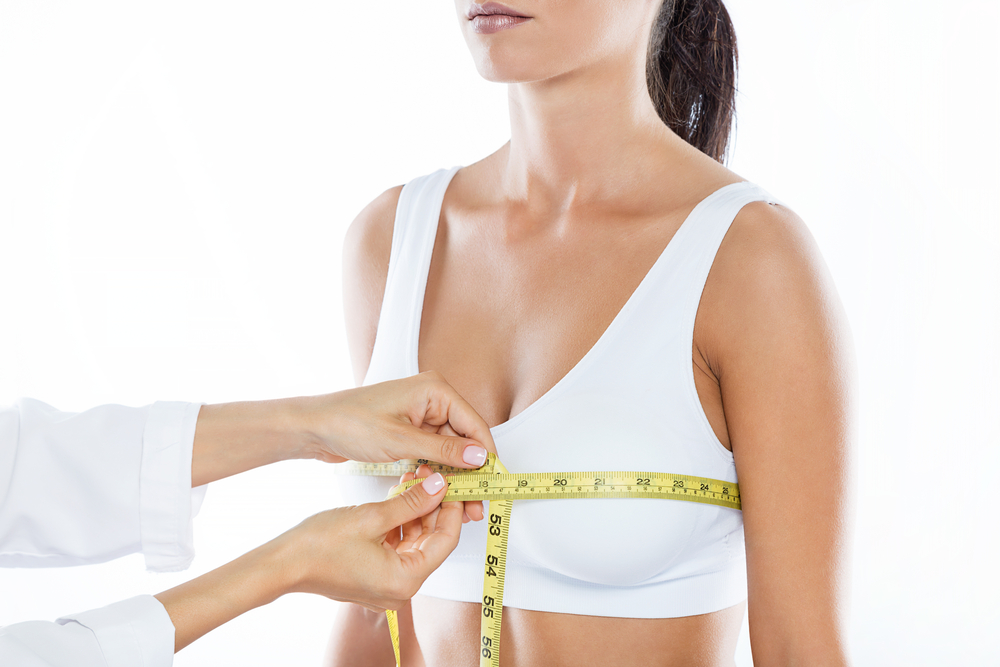 Doctor with measure tape measuring the size of the patient's breast