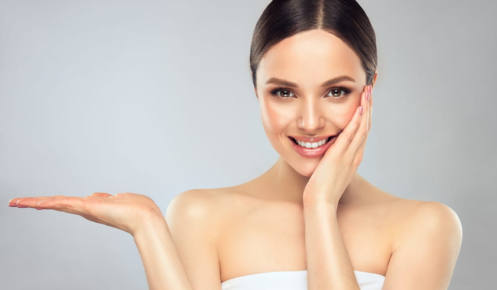 Beautiful woman with clean fresh skin .Sweet smiling girl expressive pointing to the side