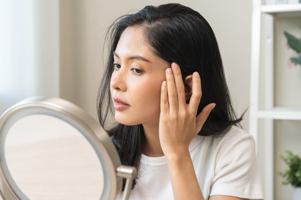 Anti aging beauty, happy asian young woman looking in mirror reflection at home