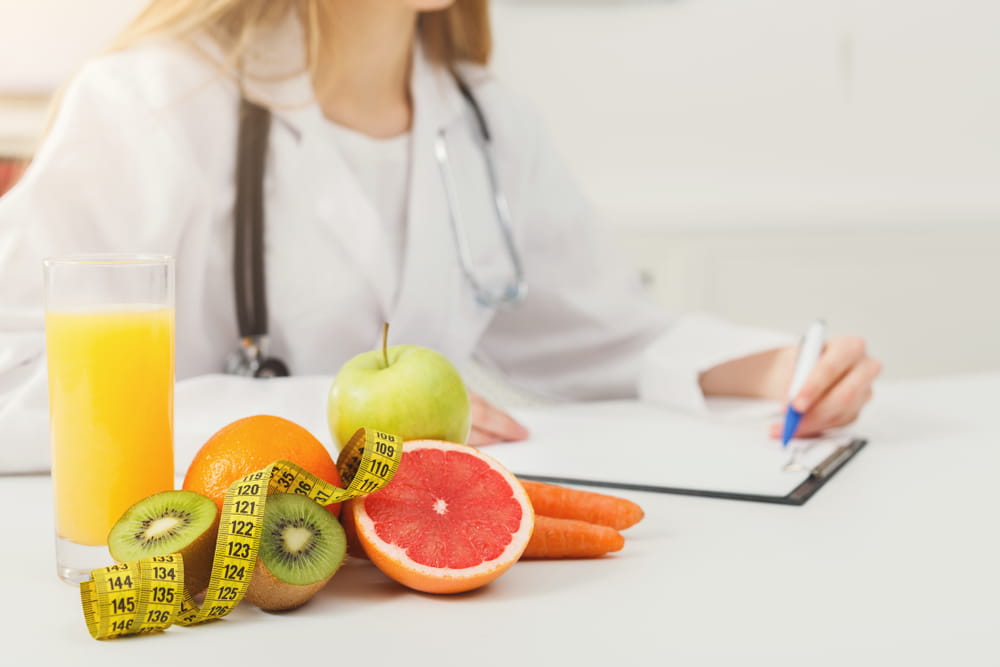 Nutritionist desk with healthy fruit, juice and measuring tape. Dietitian working on diet plan