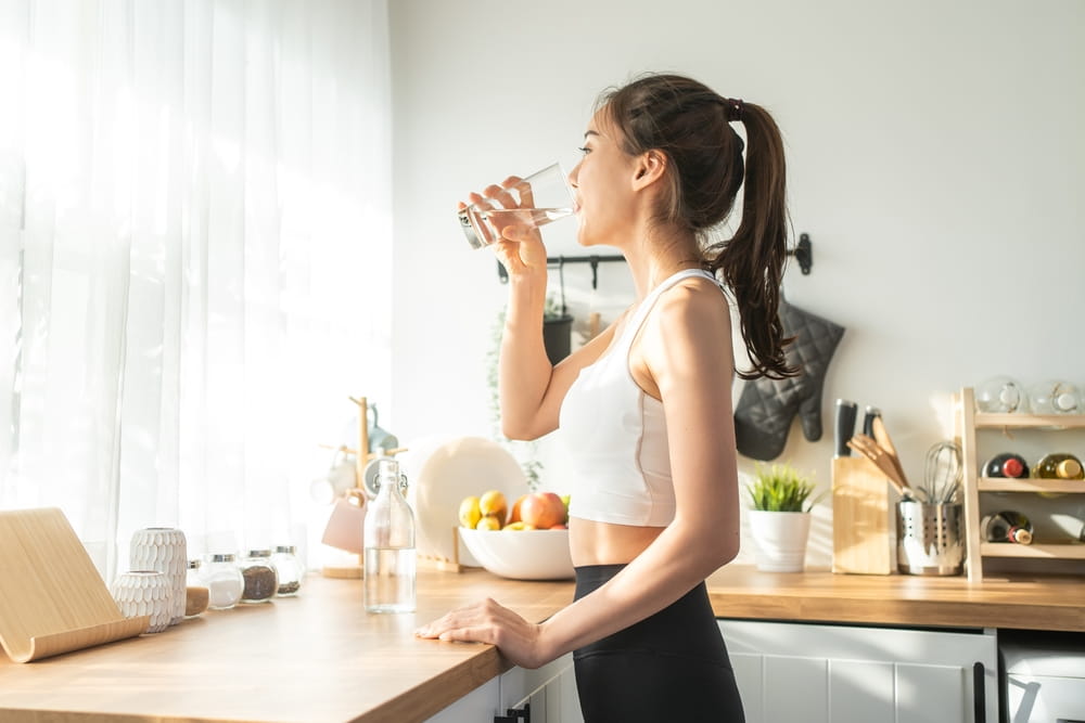 Asian beautiful woman in sportswear drink water after exercise at home.