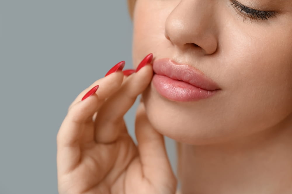 Young woman with beautiful lips on grey background, closeup