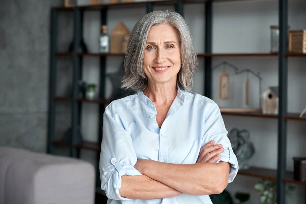Smiling confident stylish mature middle aged woman standing at home office.