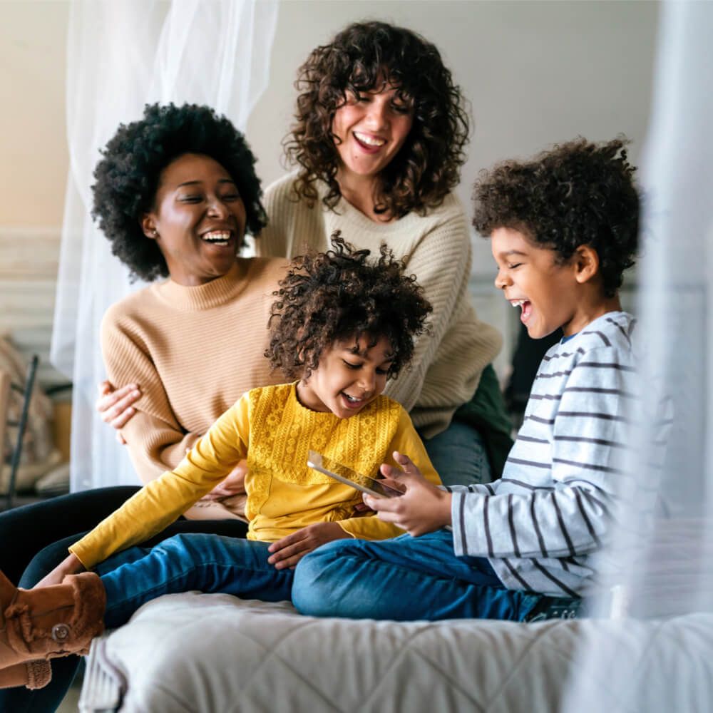 Happy multiethnic women couple having fun with kids at home