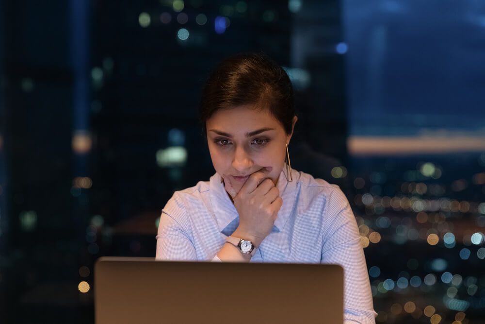 Close up thoughtful Indian businesswoman using laptop at late hours