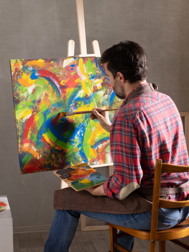 Male artist working on painting.