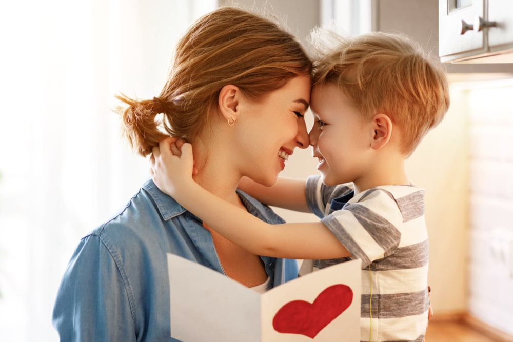 Happy little boy congratulating smiling mother