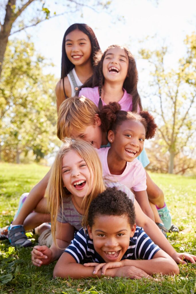 Group of children lying in a pile in a park