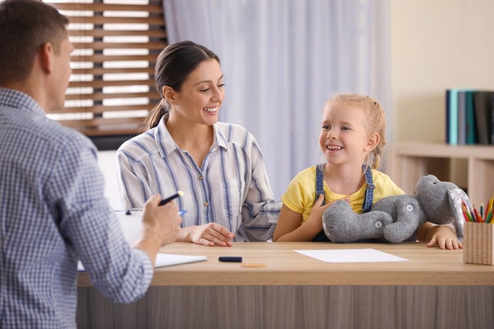 Child psychotherapist working with little girl and her mother in office