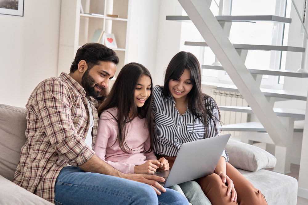 Happy family couple with child daughter using laptop