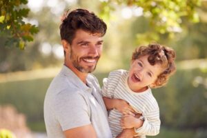 Loving Father With Son Having Fun In Park Holding Him In The Air